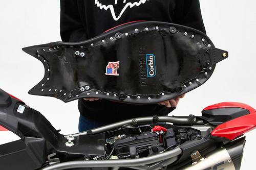 a person holding Supermoto seat showing the back side, MPN printed and mounting brackets pre-installed