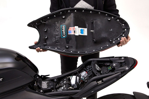 a person holding Dual seat showing the back side latch pin, MPN printed and mounting brackets pre-installed