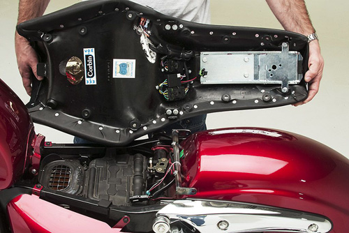 a person is holding Rumble seat showin back side heater wiring and mounting brackets pre-installed and airbox is also shown