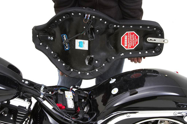 a person holding Front & Rear Solo seat showing the rear side with MPN printed, heater wiring harness and mounting brackets pre-installed