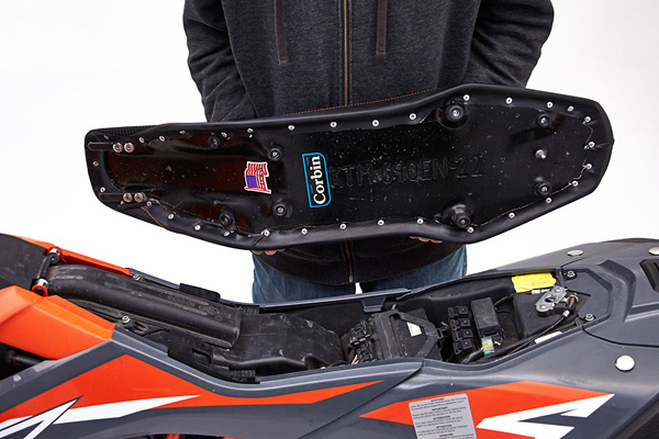 a person holding Dual Sport seat showing the rear side, MPN printed and mounting brackets pre-installed