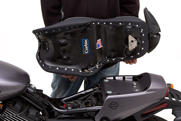 a person holding Gunfighter seat showing the rear side with MPN/Corbin Logo printed and mounting brackets pre-installed