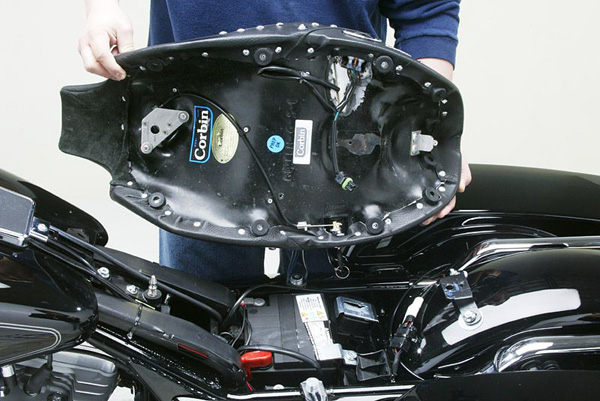 a person holding Front seat showing rear side with MPN printed, heater wiring and mounting brackets pre-installed