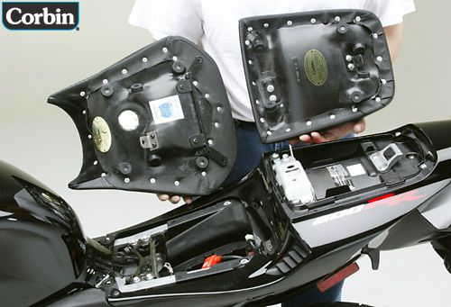 a person is holding front and rear seat showing rear side with MPN printed and mounting brackets pre-installed