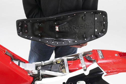 a person is holding Dual Sport seat showing rear side MPN printed and mounting brackets pre-installed