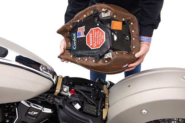 a person is holding Classic Solo seat showing rear side MPN printed, wiring harness and mounting bracket pre-installed