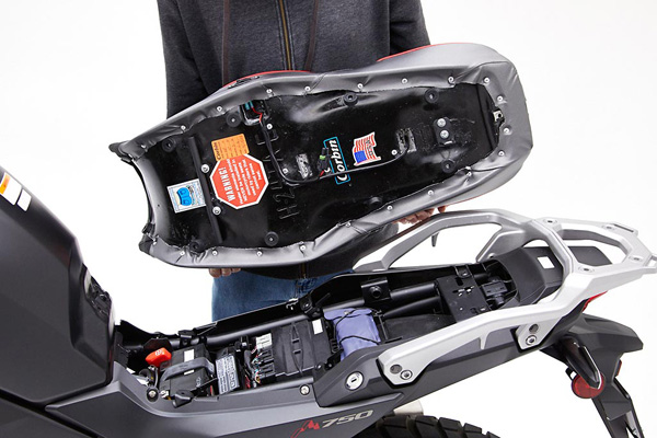 a person is holding Low Canyon Dual Sport seat showing basepan with heater wiring and mounting brackets pre-installed