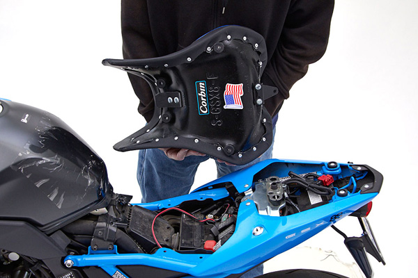 a person is holding front seat and showing basepan with mounting brackets preinstalled